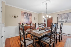 A dining room with a wooden table, chairs, and a chandelier.