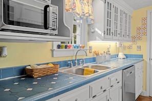 Una cocina con microondas, pileta doble y una cesta de madera en la encimera.