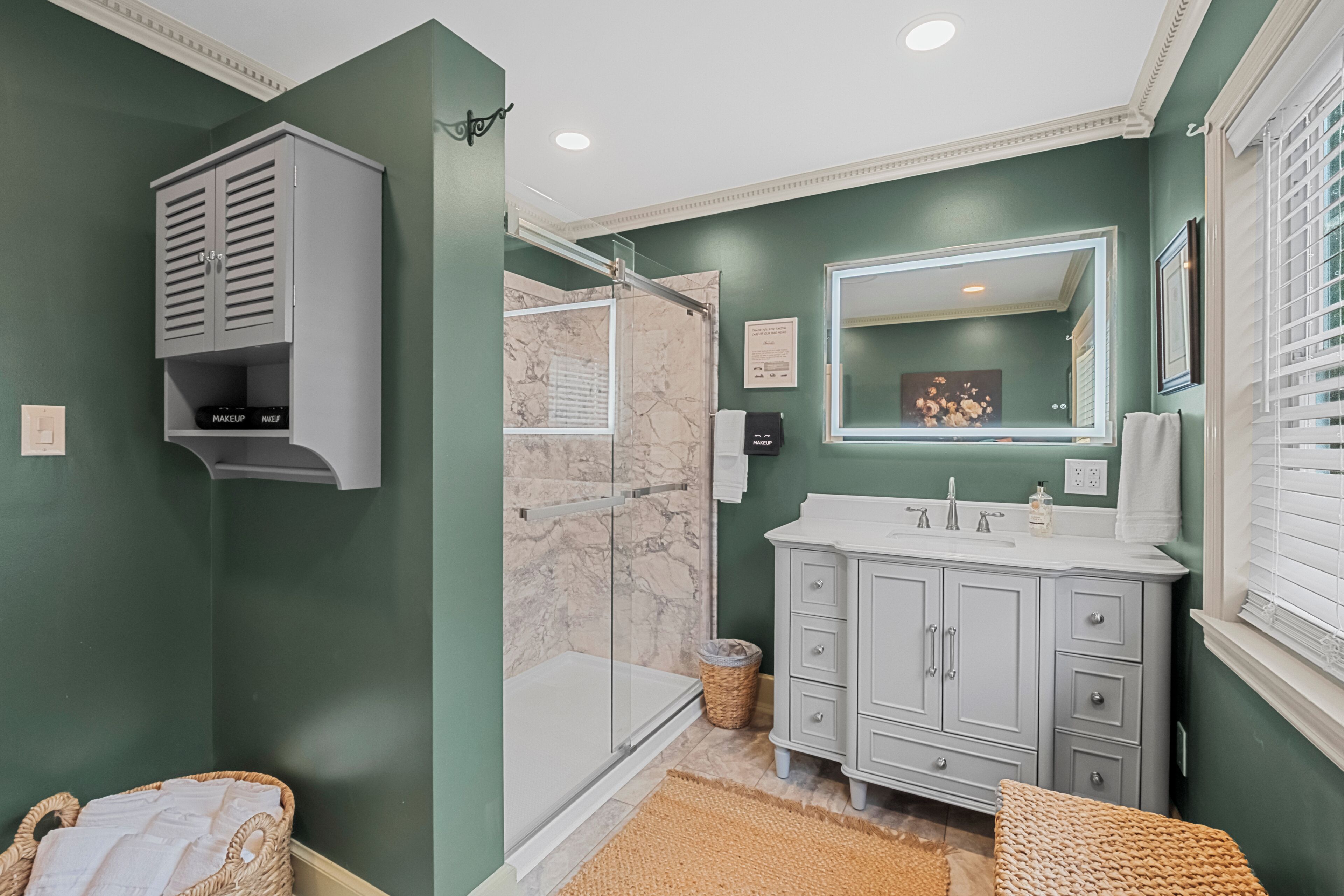 A bathroom with a shower, vanity, and a towel rack.
