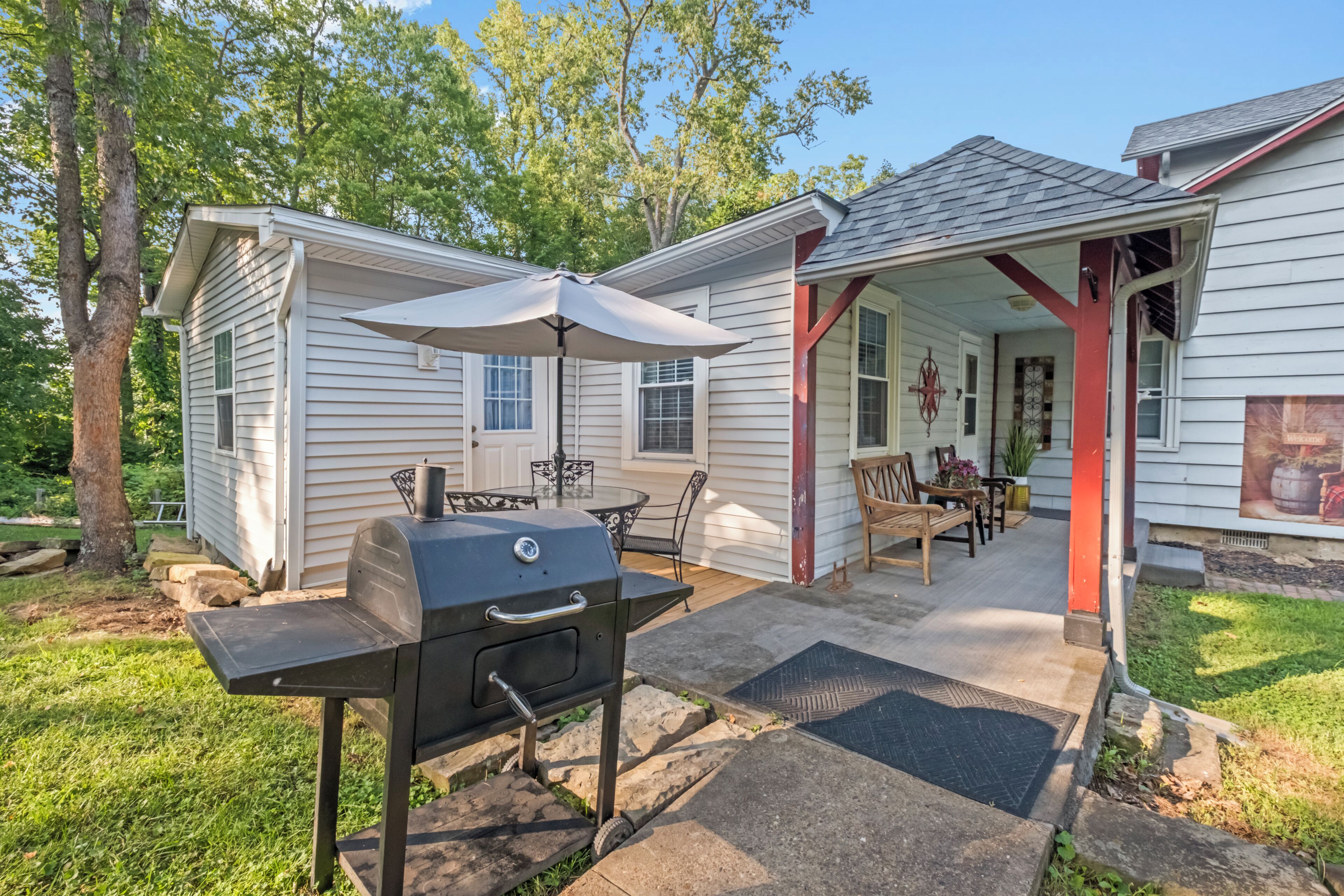 A backyard with a grill, patio furniture, and a covered seating area.