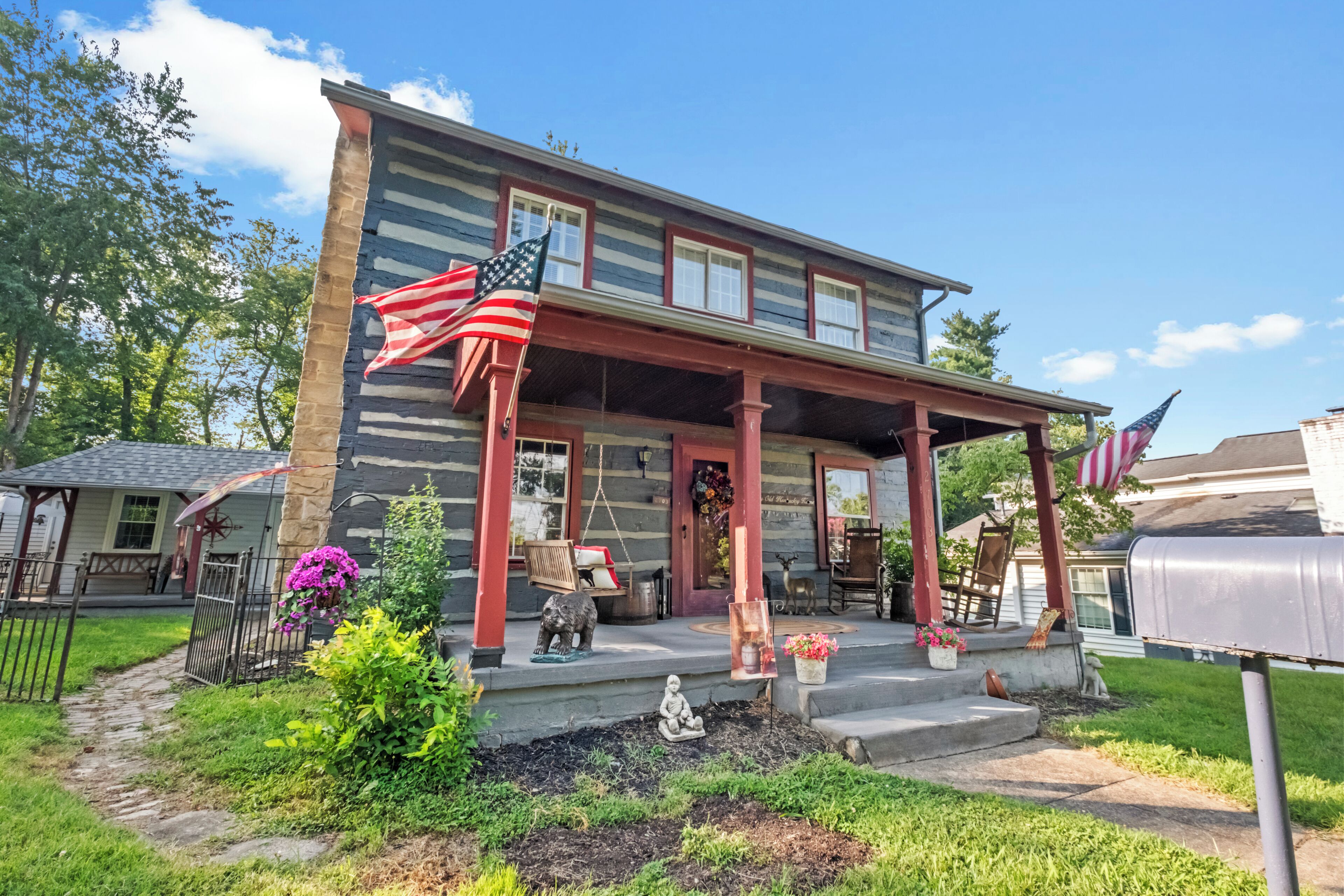 A two-story house with a porch, a mailbox, and a swing set.