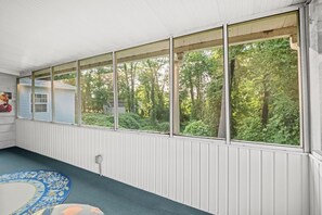 A room with a large window overlooking a forested area.