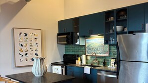 A modern kitchen with a central island, stainless steel appliances, and teal cabinetry. - Old City 2BR Condo close to Downtown and UTK: excellent walkablity (Knoxville)