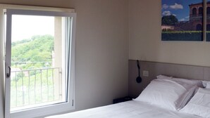 A bedroom with a bed, a window, and a painting on the wall. - Flumendosa Apartment, Stunning View of the Euganean Hills (Veneto)