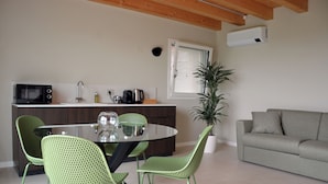 A modern kitchen with a dining area, a sofa, and a potted plant. - Flumendosa Apartment, Stunning View of the Euganean Hills (Veneto)
