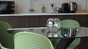 A modern kitchen with a microwave, coffee maker, and a glass vase on the counter. - Flumendosa Apartment, Stunning View of the Euganean Hills (Veneto)