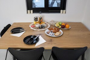 A dining table set with plates, cutlery, and a variety of food items including fruits and pastries. - Athelio Boutique Home • Private Garden • Outdoor Bar • Near Metro (Pireas)