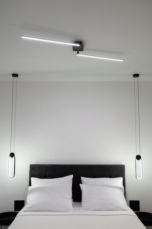 A modern bedroom with a large bed, a headboard, and two pendant lights.