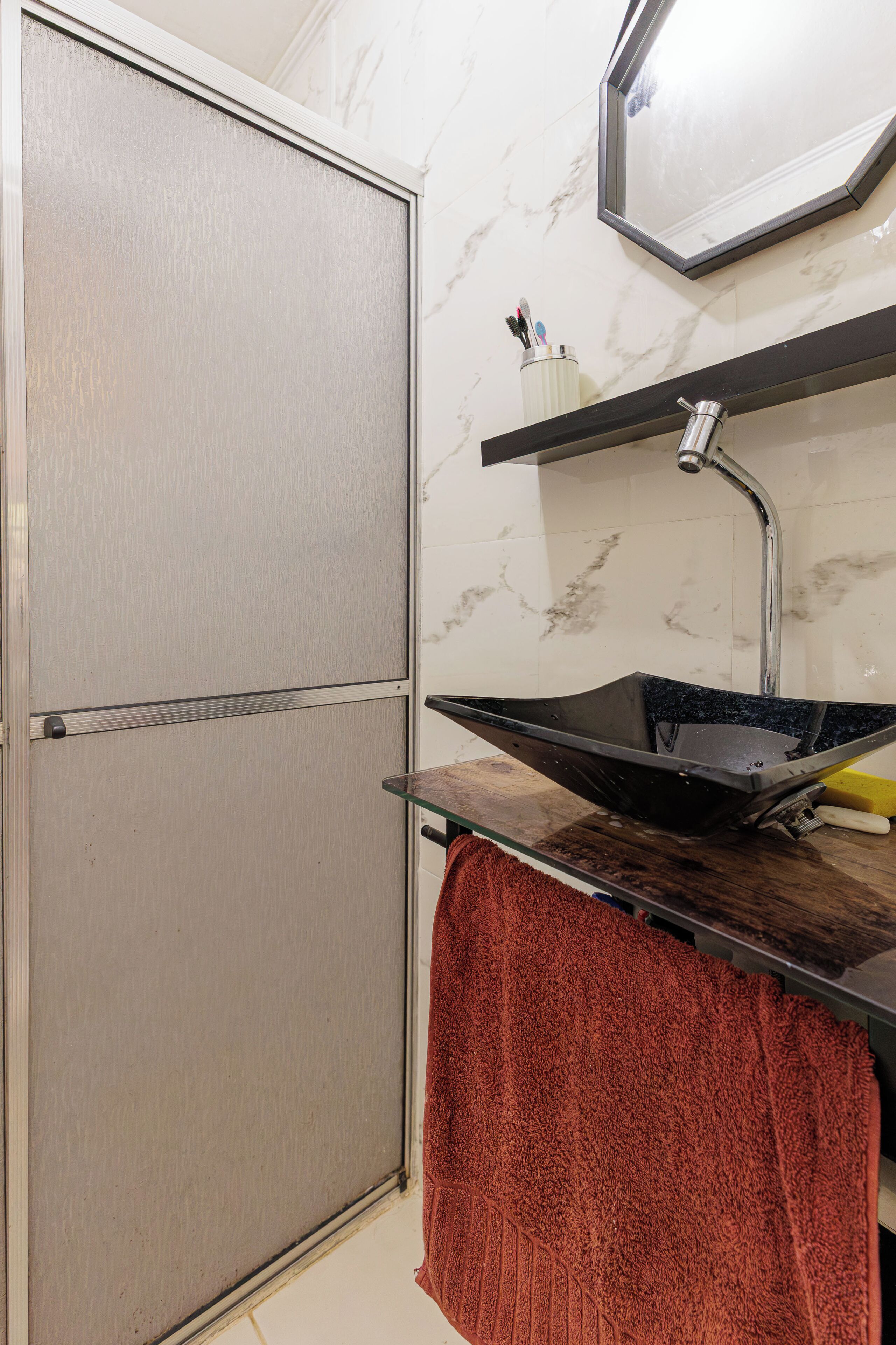 A bathroom with a toilet, a sink with a basin, a towel, and a mirror on the wall.