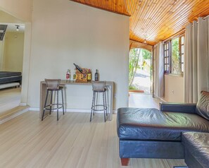 A room with a wooden ceiling, a bar area with stools, a sofa, and a view through a window. - Cabana Mata Verde Pool/Lake - Tomorrowland (Itu)