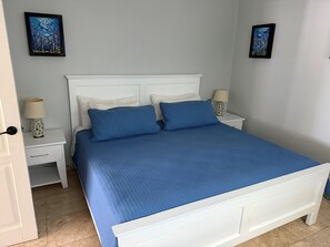 A bedroom with a white bed, two nightstands, a white door, and two wall-mounted paintings. - Oceanfront Luxury Condo (Cabarete)