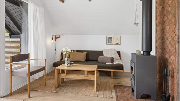 Ein gemütliches Wohnzimmer mit einer Couch, einem Holztisch, einem Sessel, einem Kamin und einer Treppe, die in einen oberen Bereich führt.