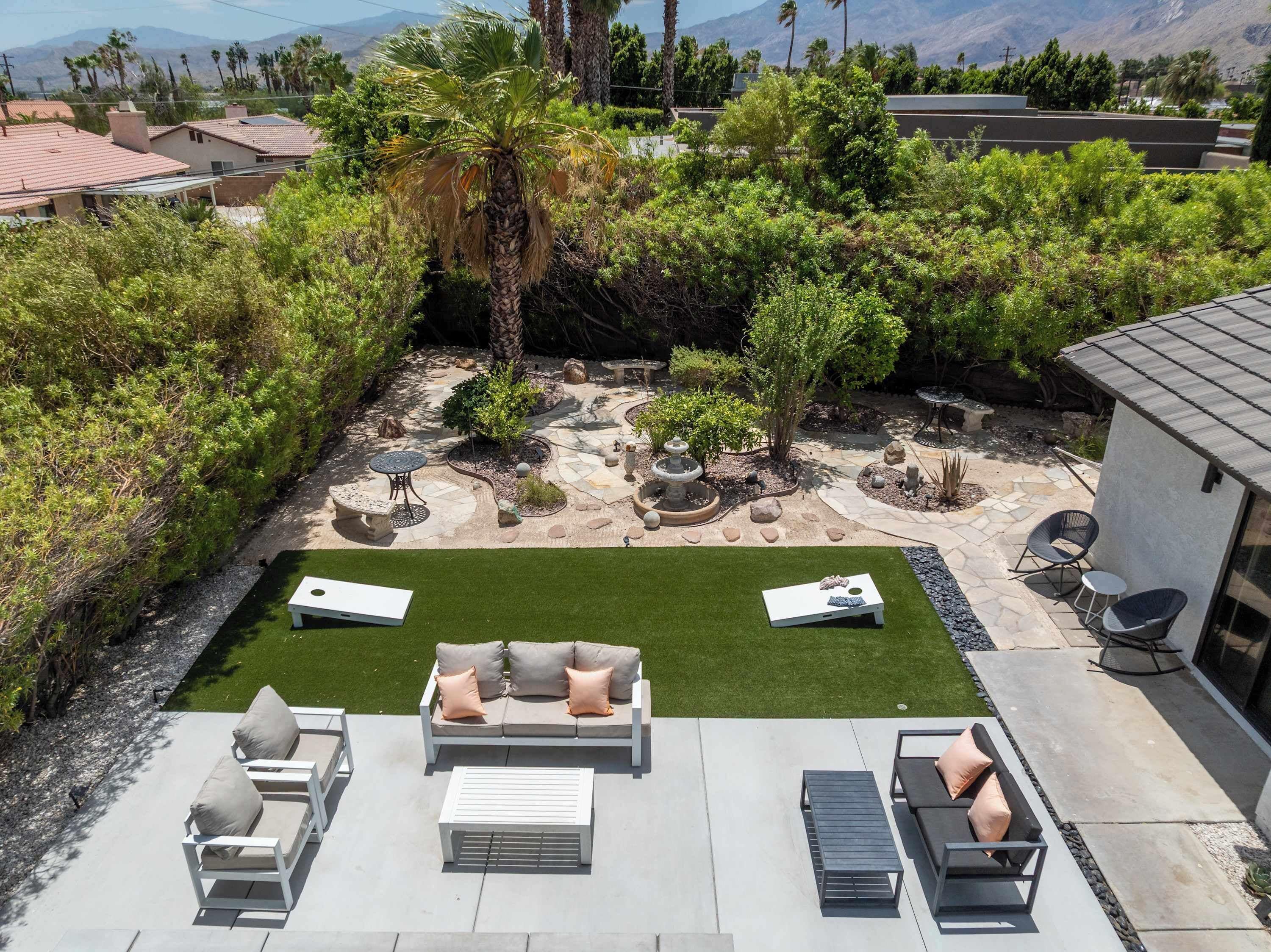 A backyard with a patio area, a lawn, and a variety of plants and trees.