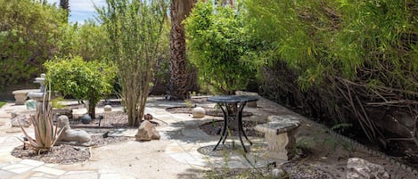 A garden with a variety of plants, a stone pathway, and a metal table.