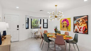 A dining area with a round table, chairs, and a modern chandelier. - Nicola Oasis Resort-Style Palm Springs Oasis | Saltwater Pool, Spa & Mountain Views (Palm Springs)