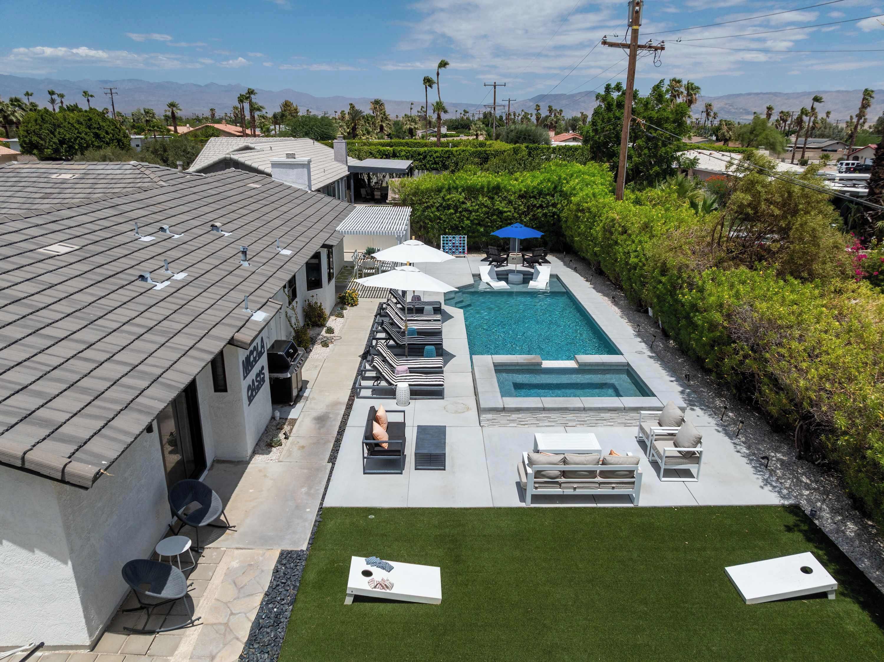 A residential property with a swimming pool, outdoor seating, and a view of mountains.