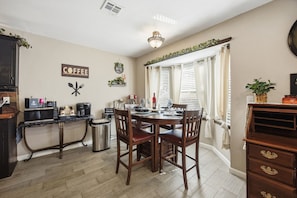 A dining area with a table set for two, a coffee station, and a trash bin. - Cozy Getaway, an ultimate Tulsa suburb retreat and a backyard oasis. (Tulsa)