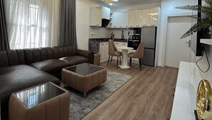 A modern living room with a sectional sofa, a coffee table, and a dining area with chairs. - Unique 2-Bedroom Apartment in Lekki 1 with Jacuzzi, Fast Wi-Fi & 24/7 Power (Lagos)