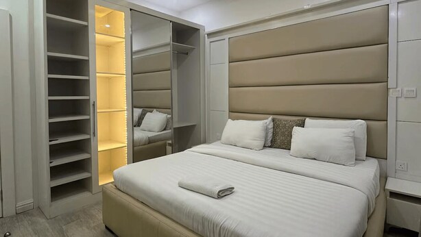 A modern bedroom with a large bed, built-in wardrobe, and recessed ceiling lighting. - Unique 2-Bedroom Apartment in Lekki 1 with Jacuzzi, Fast Wi-Fi & 24/7 Power (Lagos)