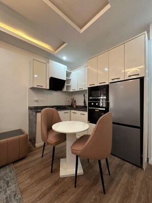 Een moderne keuken met een centraal eiland, twee stoelen en een ingebouwde oven.
