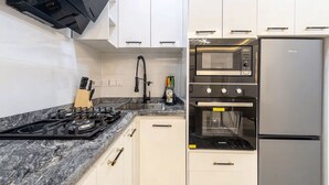 A kitchen with a gas stove, oven, microwave, and a refrigerator. - Unique 2-Bedroom Apartment in Lekki 1 with Jacuzzi, Fast Wi-Fi & 24/7 Power (Lagos)