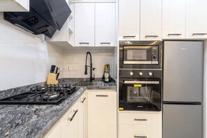Eine Küche mit Gasherd, Backofen, Mikrowelle und Kühlschrank.