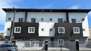 A multi-story residential building with a white and dark facade, multiple windows, and a gated entrance. - Unique 2-Bedroom Apartment in Lekki 1 with Jacuzzi, Fast Wi-Fi & 24/7 Power (Lagos)