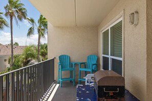 A balcony with two turquoise chairs, a small table, and a grill. - Seas the day! Just a 5 minute walk to the beach! 2bd 2 bath sleeps 8 (South Padre Island)