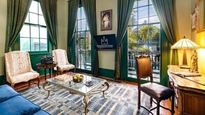 Quarto com duas poltronas, uma mesa de centro de vidro, um tabuleiro de xadrez e um abajur.