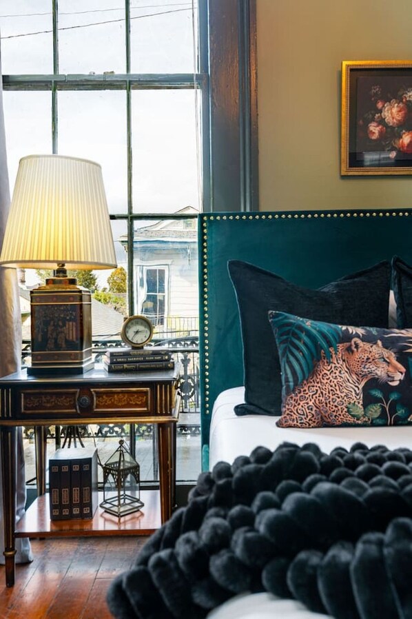 A room with a bed, a lamp, a clock, and a view through a window.