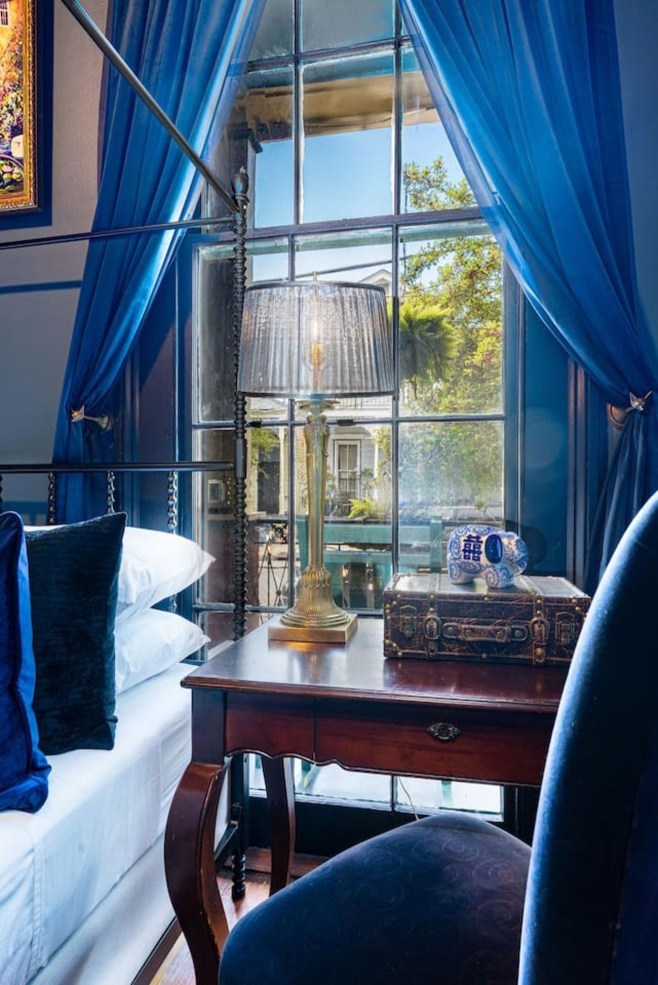 A room with a bed, a desk with a lamp, and a window with curtains.