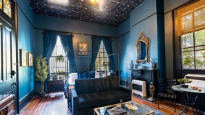 Um quarto com lareira, um sofá, uma mesa de centro e uma área de jantar com cadeiras.