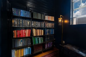En bokhylla full av böcker, en golvlampa och ett fönster med utsikt över himlen.