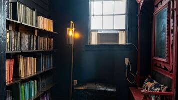 A room with a bookshelf, a window, a lamp, and a mirror.