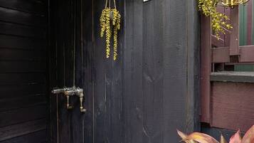 A dark wooden door with a 'SHOWER' sign, a hanging light fixture, and a plant on the right.
