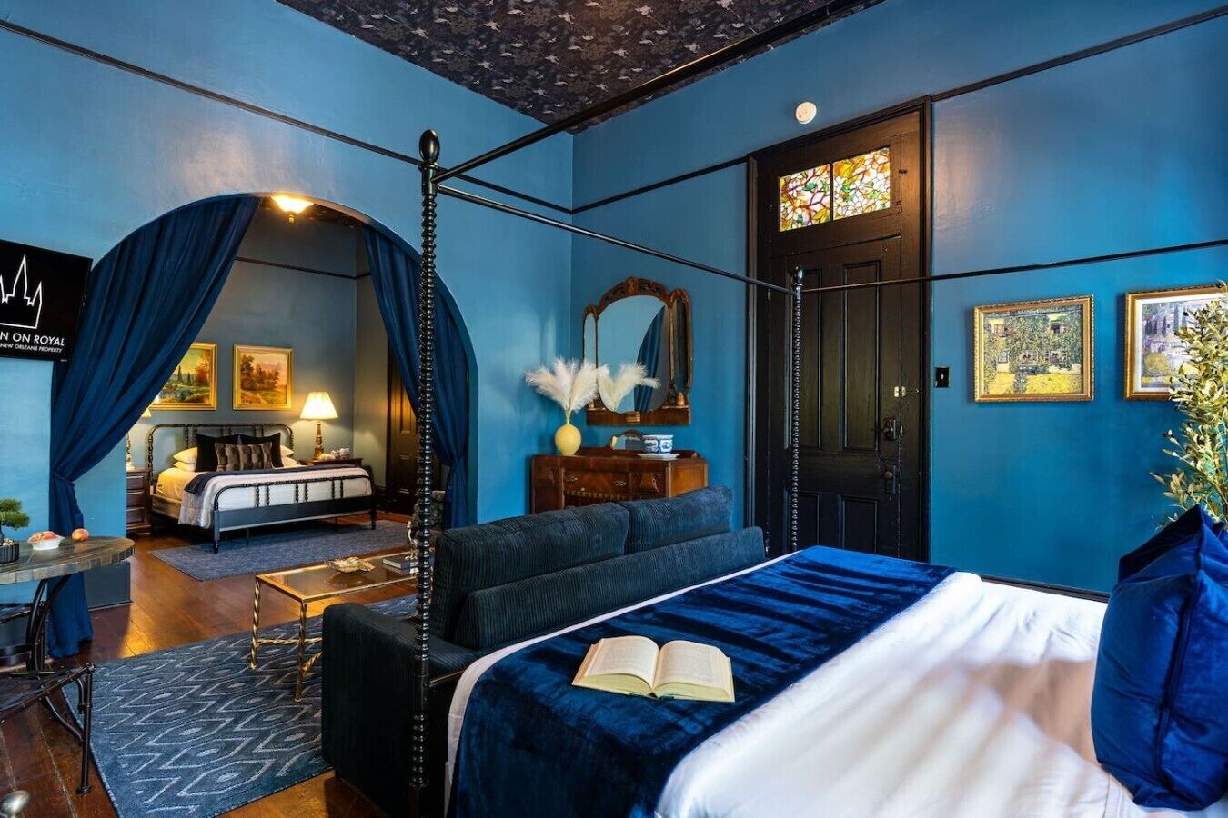 A room with a bed, a desk, a chair, a mirror, and a door.