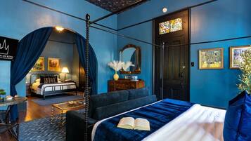 A room with a bed, a desk, a chair, a mirror, and a door.