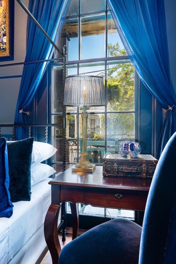 Een kamer met een bed, een bureau, een lamp en een raam met gordijnen.