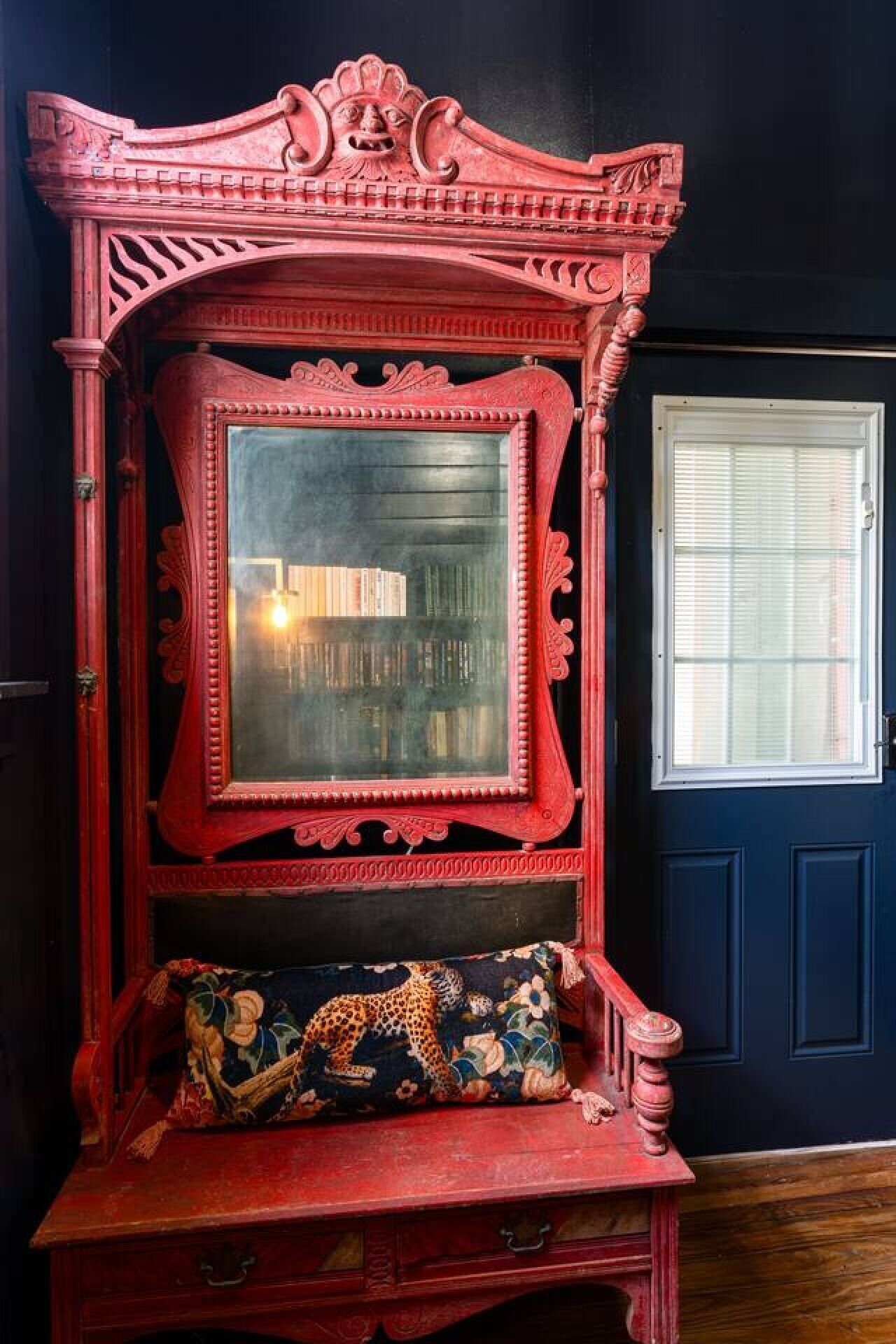 A red ornate wooden bench with a glass panel and a leopard print cushion.