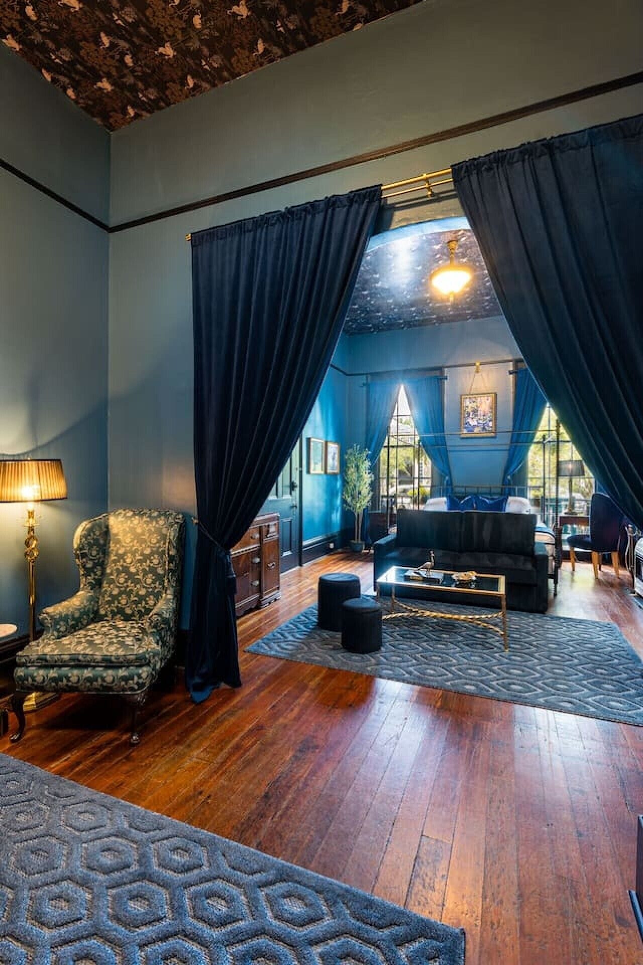 A room with a large window, a sofa, a chair, and a lamp.