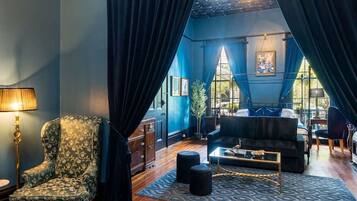 A room with a large window, a sofa, a chair, and a lamp.