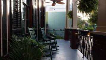 A covered outdoor seating area with chairs and potted plants.