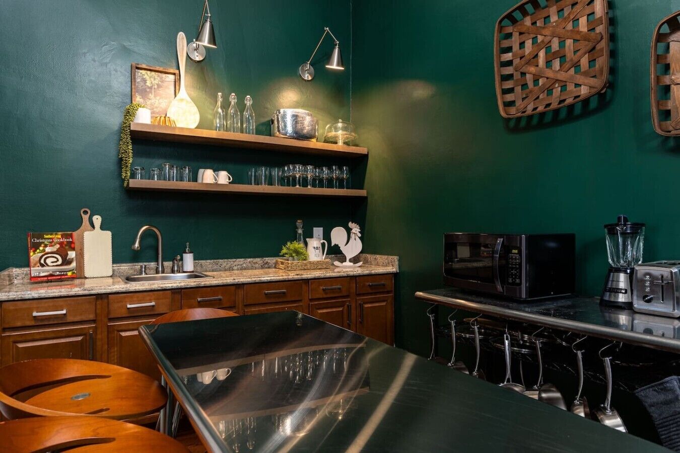 A kitchen with a stainless steel table, wooden cabinets, a microwave, and a blender.