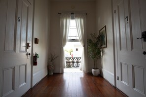A hallway with wooden flooring, white doors numbered 6 and 7, a potted plant, and a painting on the wall.