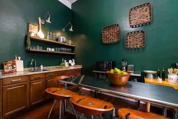 A kitchen with a central island, bar stools, a microwave, and a blender.