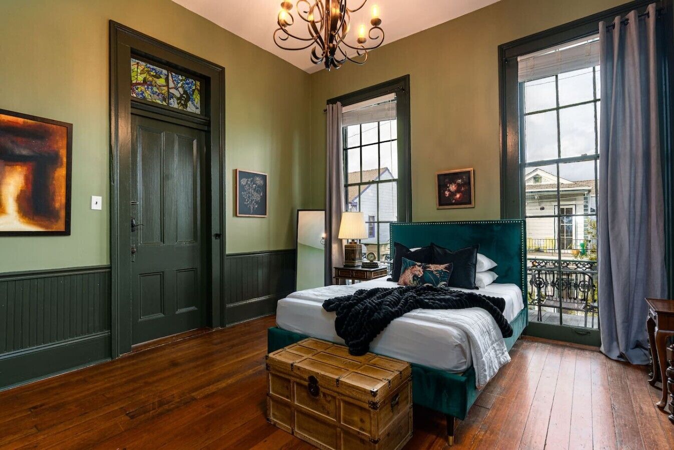 Une chambre à coucher avec un grand lit, une commode, une fenêtre donnant sur un beau paysage et un lustre.