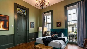 Un dormitorio con una cama grande, un aparador, una ventana con vistas y una araña.