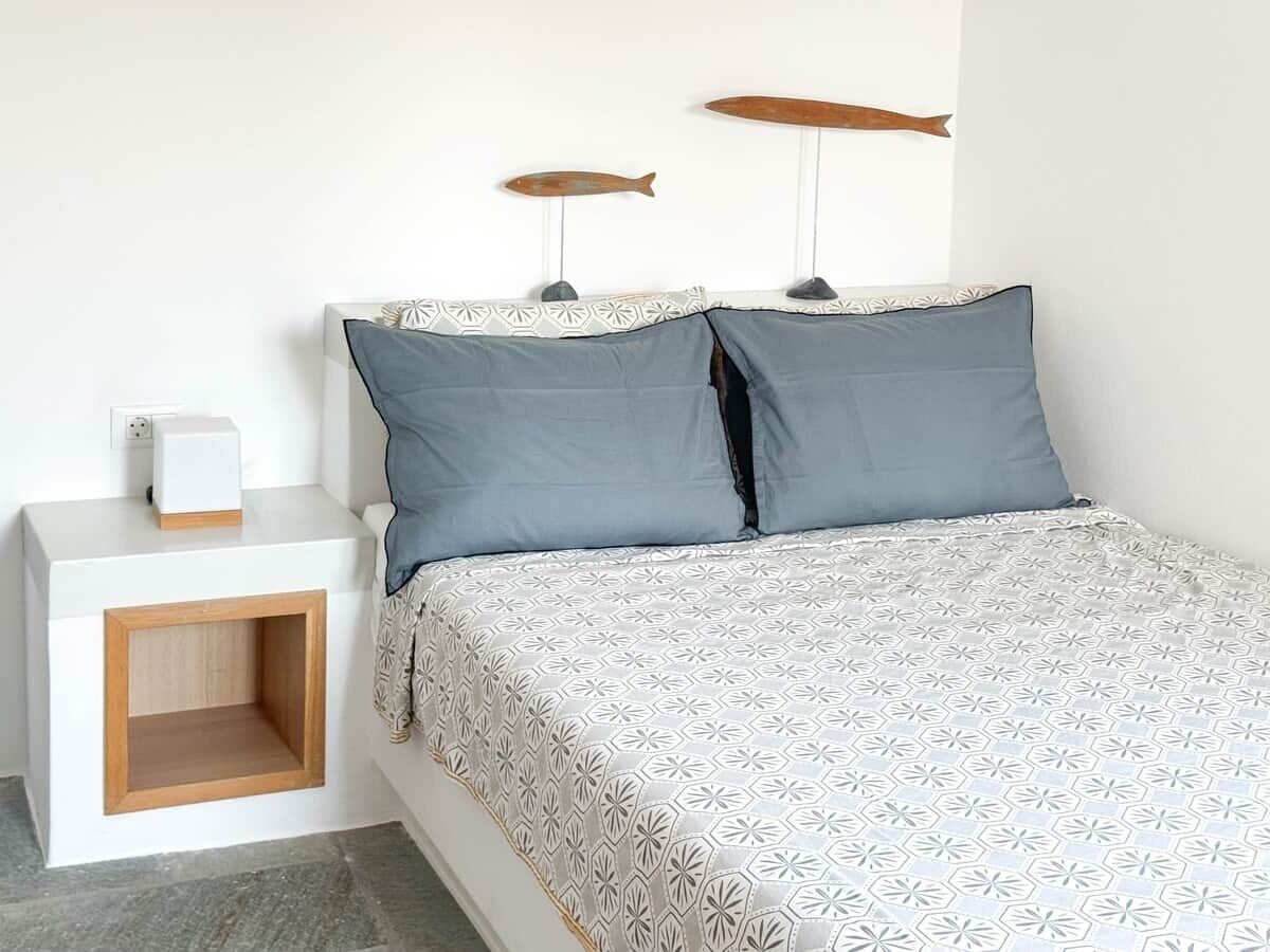 A bedroom with a bed, bedside table, and decorative fish on the wall.