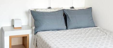 A bedroom with a bed, bedside table, and decorative fish on the wall.