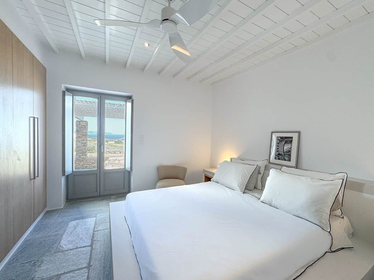 Una camera da letto con un letto grande, una sedia, un comodino e una finestra con vista.
